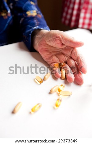 An old hand holding pills on a table