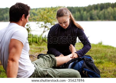 A woman applying an ankle bandage on a male camper