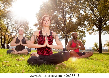 A group of people meditation in the park - taken into the sun with lens flare