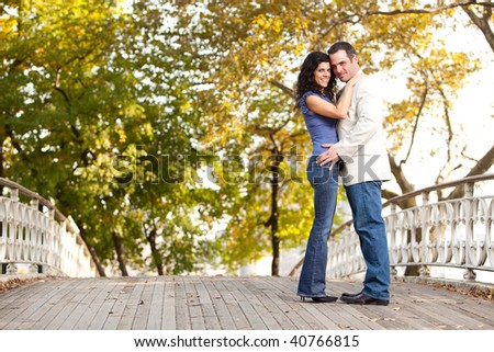 A happy couple in the park looking at the camera and hugging