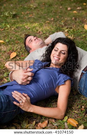 A man and woman relaxing in the park laying in the grass and dreaming - focus on the woman