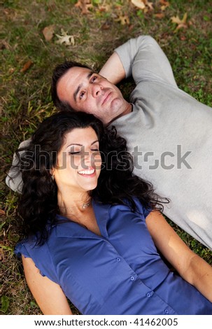 A couple day dreaming while laying on grass