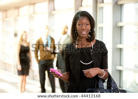 A business woman with a smart phone with colleagues in the background