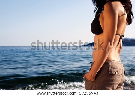 A woman standing on the beach looking out at the horizon