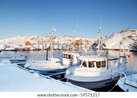 A dock in southern Norway with boats covered in snow