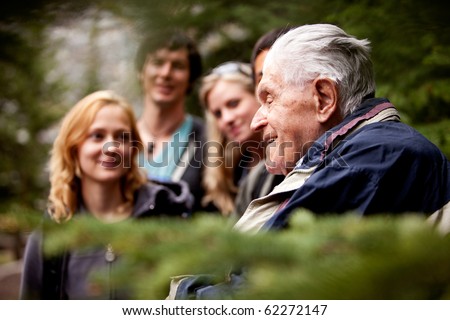 An elderly man telling stories to a group of young people