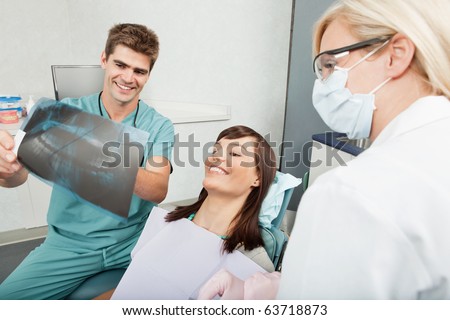 Smiling male dentist explaining the details of x-ray to a beautiful female patient