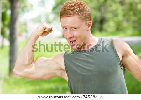 Young muscular man showing his biceps against blur background