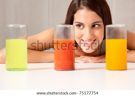 A woman looking at three science beakers filled with colored liquid