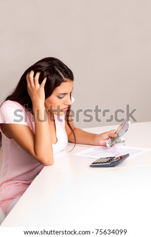 A worried woman counting money and planning a budget