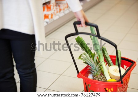 High angle view of human hand carrying red basket filled with fruits and vegetables