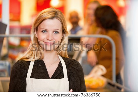 Closeup of a young shop assistant with customer in the background Closeup of a young shop assistant with customer in the background
