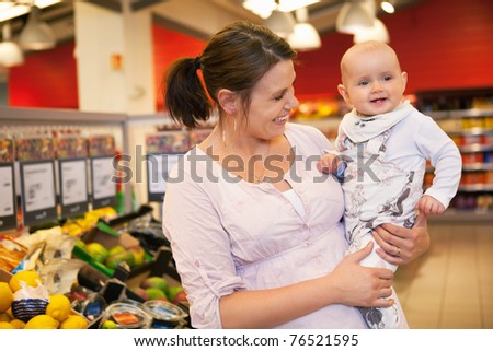 Happy mother carrying child in supermarket