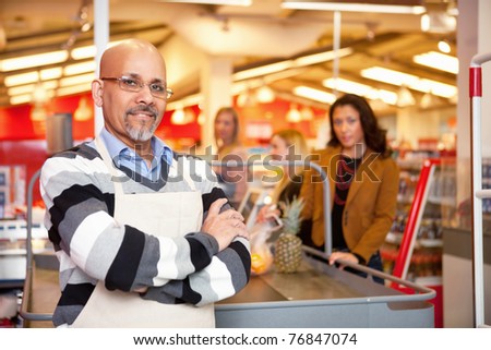 Portrait of a grocery store cashier standing at a checkout counter