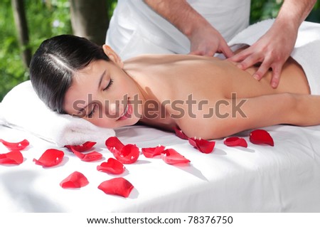 Beautiful woman getting massage and spa treatment in natural setting