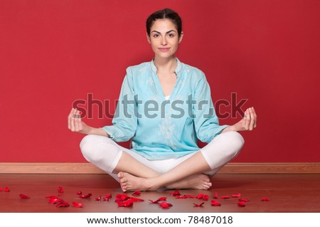 Portrait of young beautiful female practicing yoga with rose petals on floor