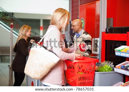 Customer shopping in supermarket with people in the background