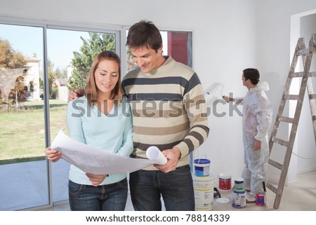 Couple going through house plan while painter in the background