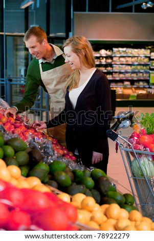 A woman buying groceries in a supermarket receiving help from a shop assistant