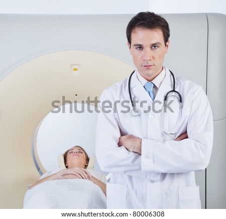 Serious doctor looking at camera in front of ct scanner