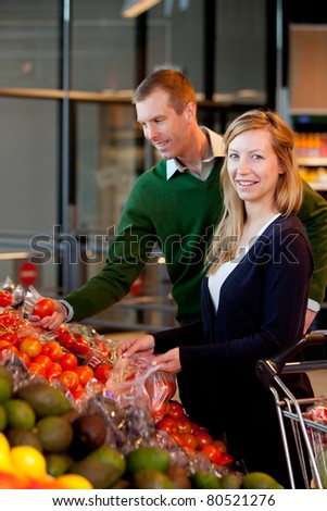 A happy couple buying fruit and vegetables in a supermarket