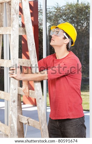 Architect wearing helmet and eyegear and holding ladder