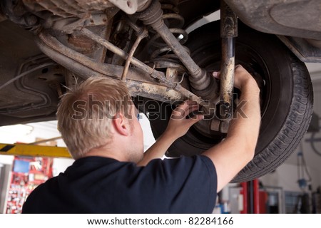 A male mechanic inspecting a CV joint on a car in an auto repair shop