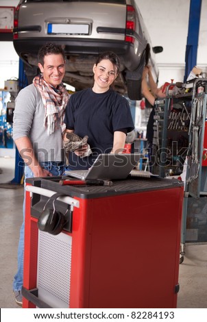 Woman mechanic going over work order on laptop with customer man
