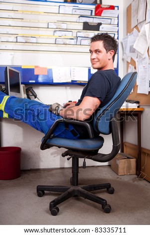 A relaxed auto mechanic leaning back in a chair in an office