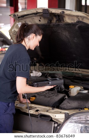 A happy woman mechanic with a smile using an engine diagnostics tool