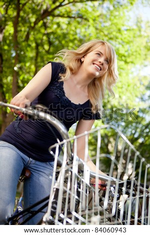 Attractive young female riding a bike through green nature