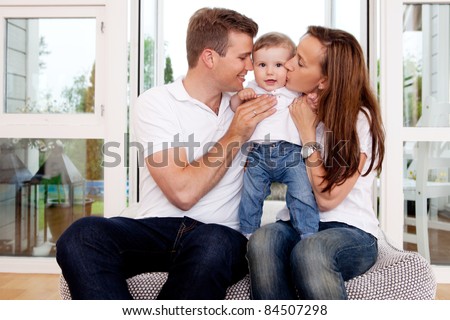 Mother and father hugging and kissing son in home interior