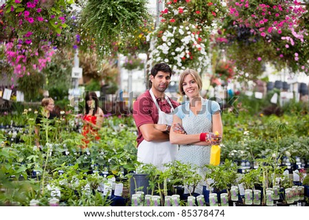 Portrait of florists at greenhouse with people in background