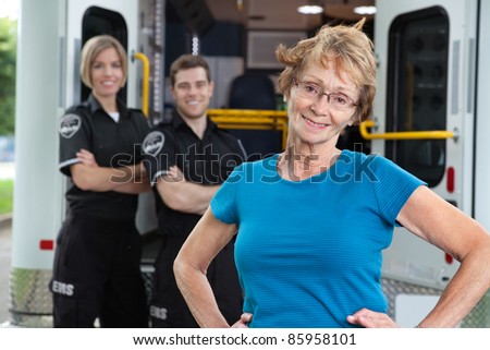 Portrait of elderly patient with ambulance workers in background