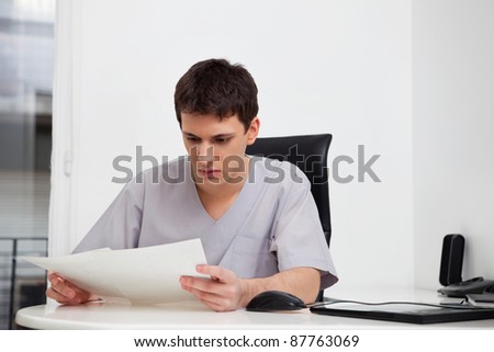 Serious male doctor reading reports of patient