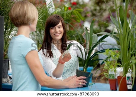 Worker helping customer with plant in garden center