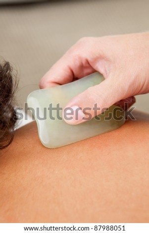Detail of back fo young male receiving gua sha acupuncture treatment