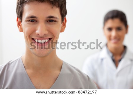 Portrait of happy male doctor standing with female doctor standing in background