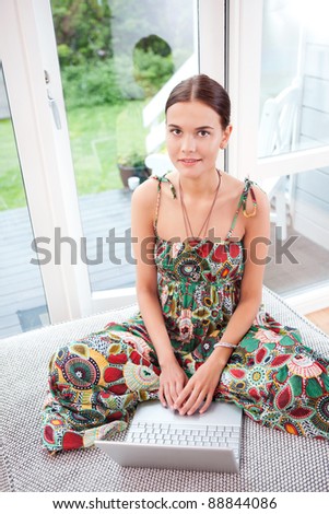 Portrait of a smiling young woman using a laptop while sitting on couch