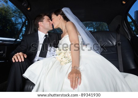 Loving newlywed bride and groom in limousine