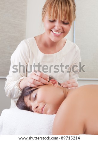 Acupuncturist placing needle in ear in auricular acupuncture treatment