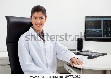 Portrait of pretty female dentist sitting at her desk with teeth x-ray on screen