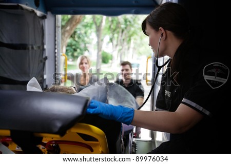 EMT worker listening to heart of elderly patient
