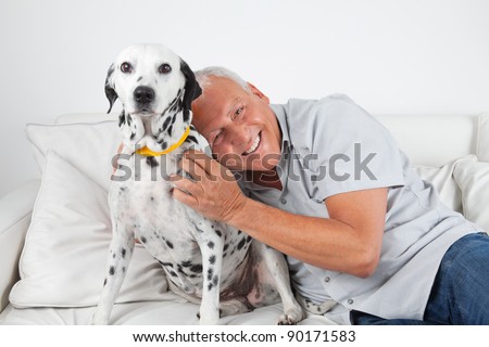 Portrait of senior man sitting on sofa with his pet dog at home