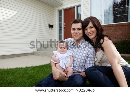 Portrait of couple with their adorable daughter sitting in front of house