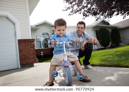 Happy father teaching his adorable son to ride a tricycle