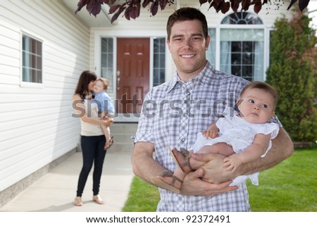 Portrait of man holding his daughter with wife standing behind holding son