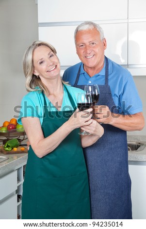 Portrait of smiling couple toasting wine glasses in the kitchen