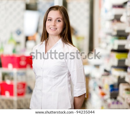 Portrait of a young attractive pharmacist standing in a pharmacy interior looking at the camera