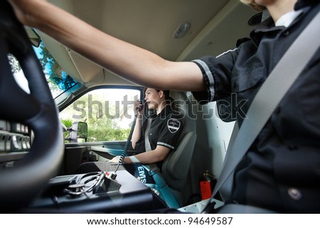 Abstract ambulance interior with female paramedic talking on radio with dispatcher